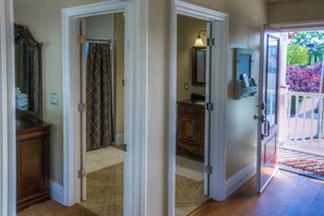 A hallway leading to a bathroom with a shower curtain, a vanity with a mirror, and a door leading outside. - Sleeps 6 + Private Yard + Gazebo + BBQ | Walk to Downtown Dining | Bliss House (Paso Robles)