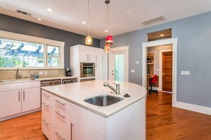 A modern kitchen with a central island, stainless steel appliances, and pendant lighting.
