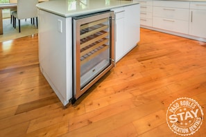 Efficient kitchen with refrigerator and glass door freezer, complemented by a dining area with chairs.