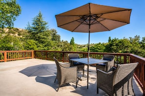 An outdoor patio with wicker furniture and a table, surrounded by a wooden railing.