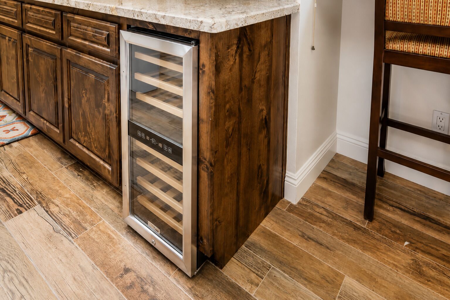 Cocina con armarios de madera, refrigerador de acero inoxidable y encimera de mármol.