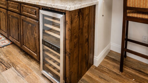 Cocina con armarios de madera, refrigerador de acero inoxidable y encimera de mármol.