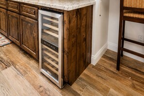 Cocina con armarios de madera, refrigerador de acero inoxidable y encimera de mármol.