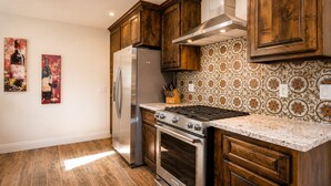 Una cocina con armarios de madera, refrigerador de acero inoxidable, estufa a gas y un salpicadero decorativo.