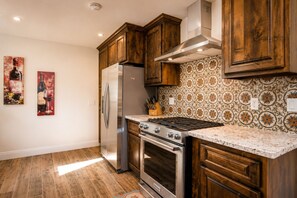 A kitchen with wooden cabinets, a stainless steel refrigerator, a gas stove, and patterned backsplash.