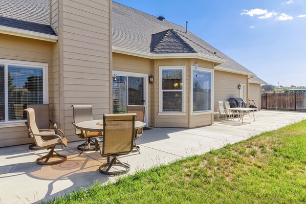 A house with a patio, outdoor seating, and a barbecue area.