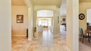 A spacious hallway with a kitchen area visible in the distance, featuring a dining table and chairs. - Fenced BBQ Yard + Game Table | Paso Robles | Peace of Mind (Paso Robles)