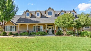 A two-story house with a front porch, a garage, and a well-maintained lawn. - Fenced BBQ Yard + Game Table | Paso Robles | Peace of Mind (Paso Robles)