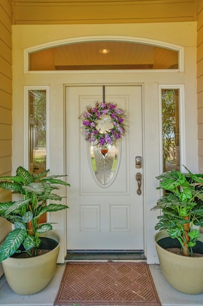 A front door with a decorative wreath, a doormat, and two potted plants on either side. - Fenced BBQ Yard + Game Table | Paso Robles | Peace of Mind (Paso Robles)