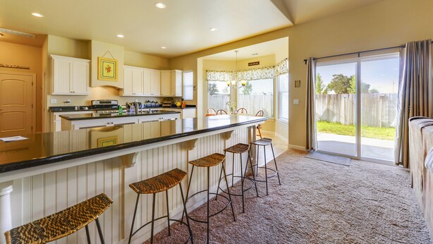 A kitchen with a bar area, white cabinets, and a large sliding glass door leading to a backyard. - Fenced BBQ Yard + Game Table | Paso Robles | Peace of Mind (Paso Robles)