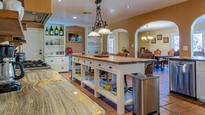 A modern kitchen with a marble countertop, stainless steel appliances, and a central island with seating.