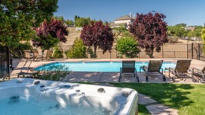 A backyard with a swimming pool, hot tub, and outdoor seating area.