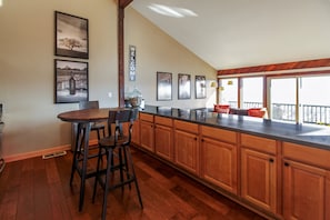 Una cocina con armarios de madera, una barra con taburetes y cuadros en la pared.