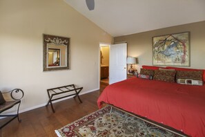 Une chambre à coucher avec un grand lit, un banc, un miroir et une porte donnant sur une autre pièce.
