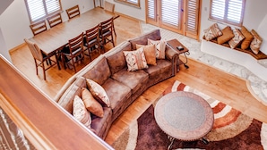 A spacious living area with a wooden dining table, a brown leather sofa, and a round coffee table.