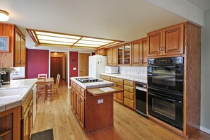 Una cocina con armarios de madera, una isla central, una estufa y un horno.