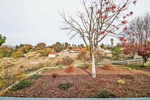 A residential area with a tree in the foreground, a white building with a red roof in the background, and a clear sky.