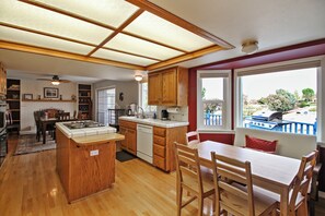 Una cocina amplia con armarios de madera, una isla central y un comedor con vistas al exterior.