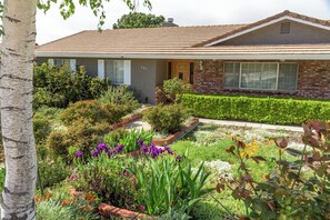 A residential house with a brick facade, a tiled roof, and a well-maintained garden with various plants and flowers. - Private Deck + Hillside Views | Paso Robles Wine Country | COF House (Paso Robles)