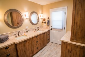Baño con armarios de madera, un lavabo y dos espejos.