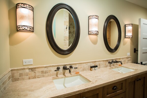 A bathroom with two sinks, a mirror, and wall sconces.