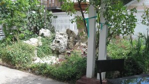 Un jardin avec une clôture blanche, un banc et un mur de pierre.