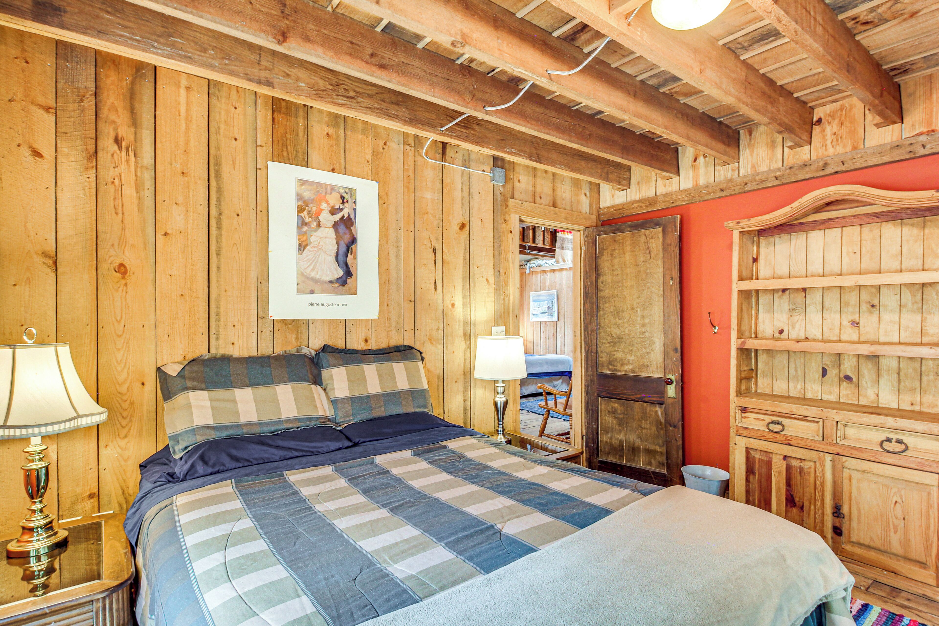 A wooden-paneled room with a bed, a nightstand, a lamp, and a wardrobe.