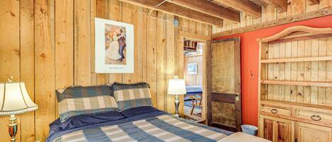 A wooden-paneled room with a bed, a nightstand, a lamp, and a wardrobe.