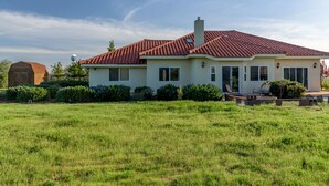 A single-story house with a red-tiled roof, a chimney, and a front porch with outdoor seating. - Vineyard Views + Jetted Tubs | Paso Wine Country | Uvae Vineyard (Paso Robles)