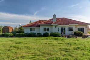 A single-story house with a red-tiled roof, a chimney, and a front porch with outdoor seating. - Vineyard Views + Jetted Tubs | Paso Wine Country | Uvae Vineyard (Paso Robles)