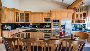 Una cucina con mobili in legno, un'isola centrale con sedie ed elettrodomestici moderni.