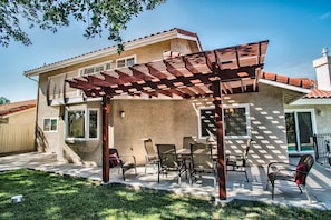 Una casa con un patio techado, una mesa de comedor y sillas.