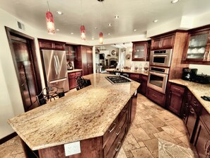 Una cocina moderna con encimeras de granito, electrodomésticos de acero inoxidable y armarios de madera.