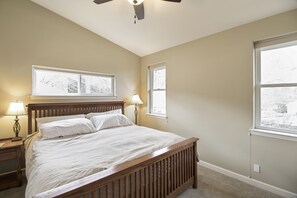 A bedroom with a wooden bed, two bedside lamps, and a ceiling fan.