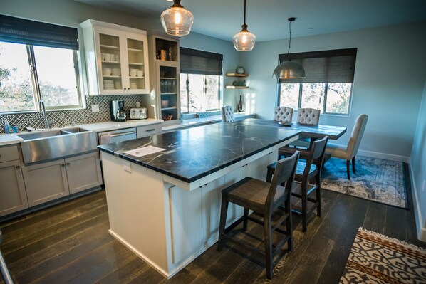 Una cocina moderna con una isla central, muebles blancos y un comedor con alfombra y sillas.