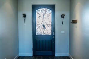 A dark blue door with decorative glass panels and a metal design, flanked by wall-mounted light fixtures.