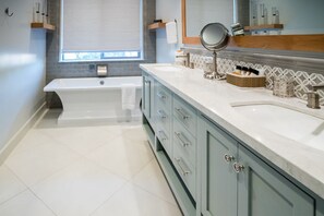 A modern bathroom with a bathtub, vanity, and a large mirror.