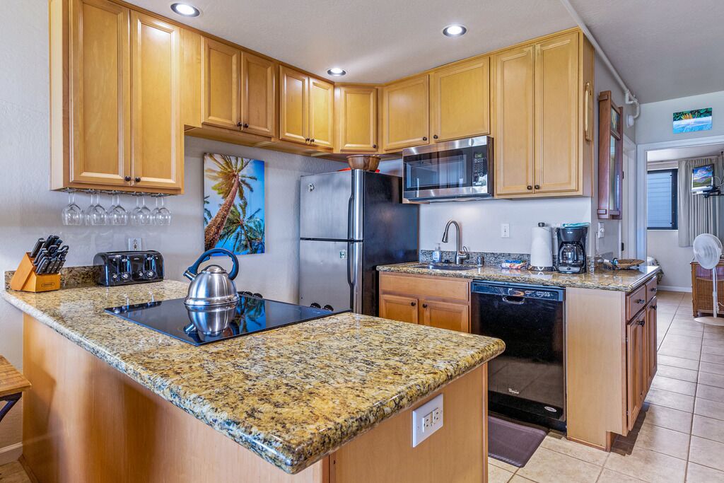 Una cocina con armarios de madera, encimeras de granito y electrodomésticos de acero inoxidable, además de una isla central.