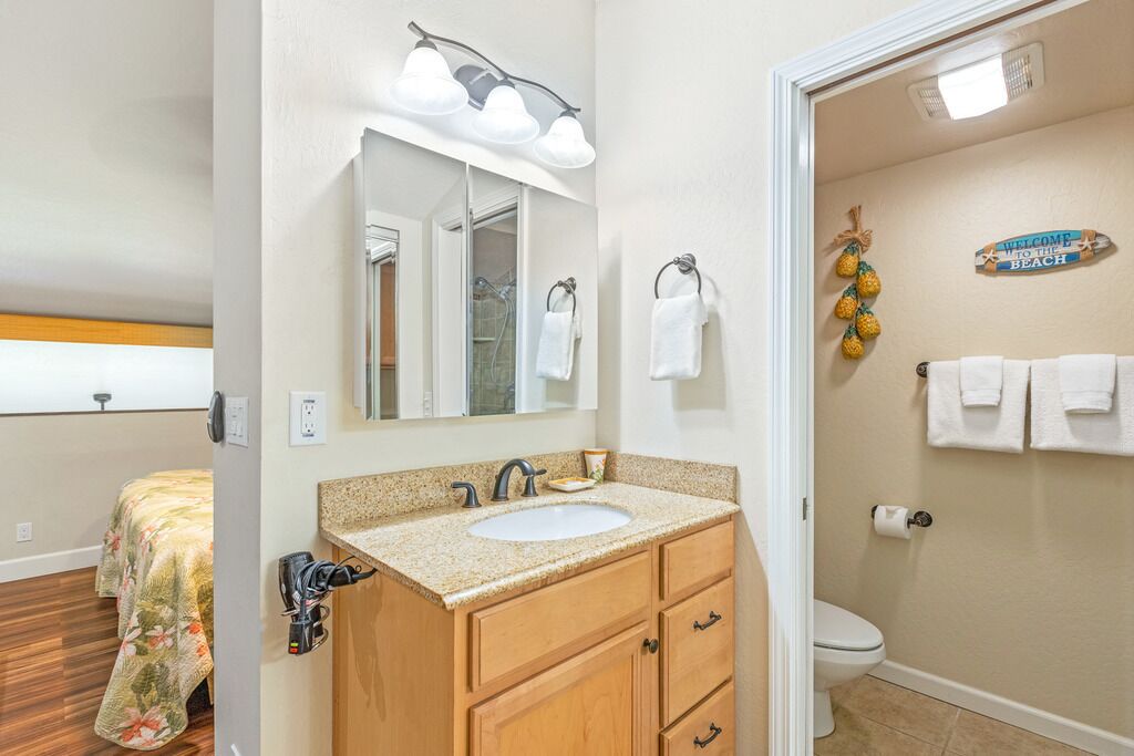 A bathroom with a sink, vanity, and toilet.