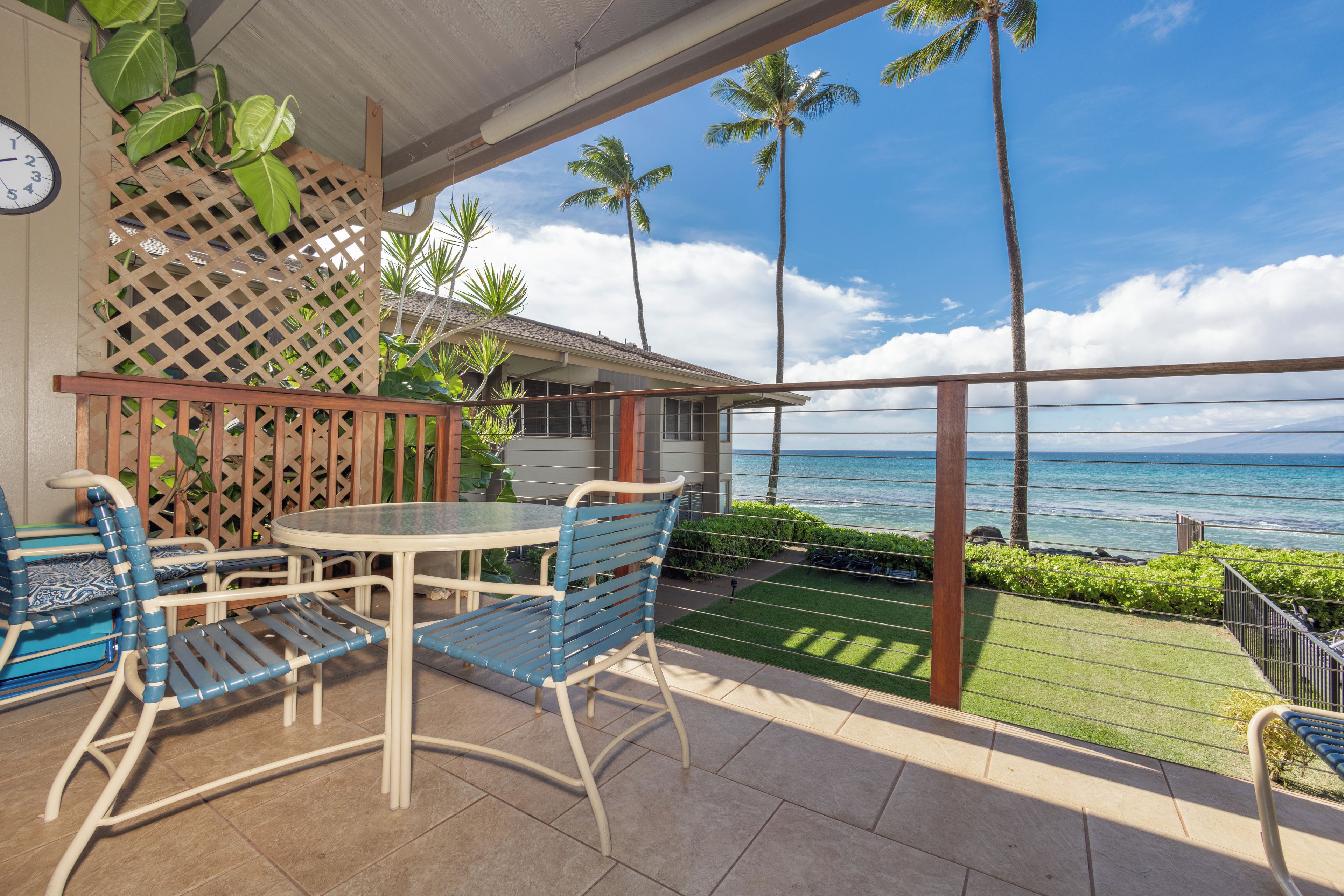 A patio with a table and chairs, a view of the ocean, and a clock on the wall.