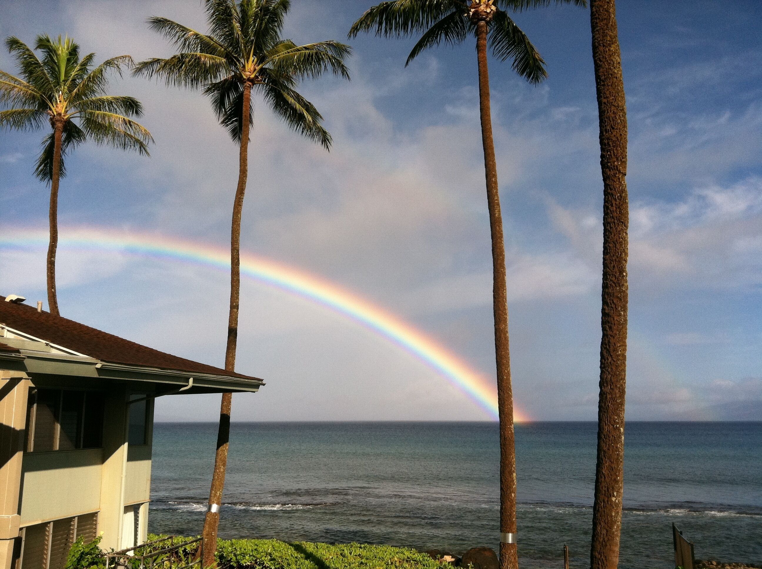 A house with a view of the ocean and a rainbow.