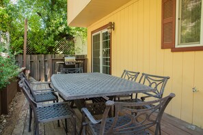 A patio with a metal table and chairs, a wooden fence, and a grill. - Firepit + Deck BBQ | Walk to Downtown Tasting Rooms | Vintage Paso (Paso Robles)