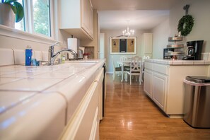 Una cucina con lavello in acciaio inossidabile, macchina da caffè e cestino.
