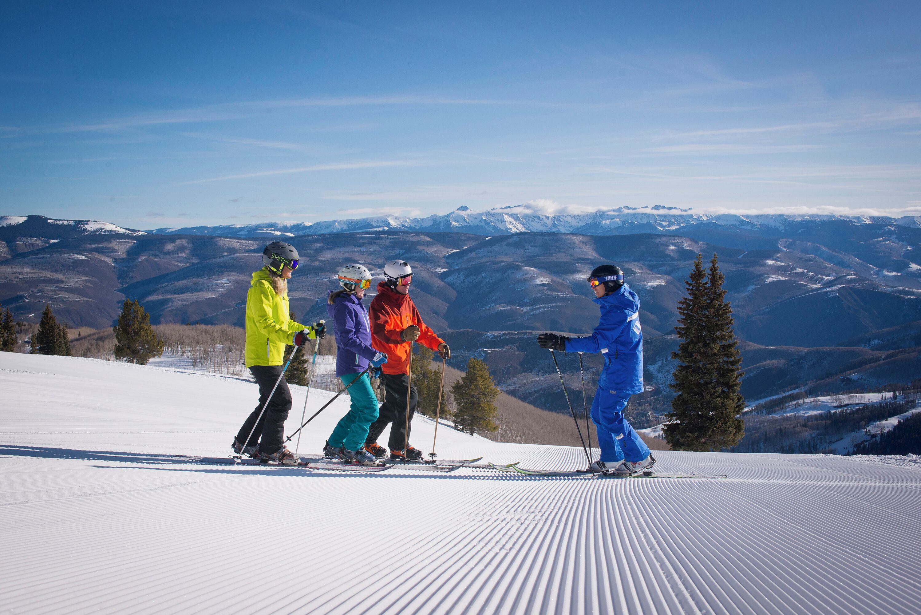 Un groupe de skieurs sur une pente enneigée, avec une chaîne de montagnes en arrière-plan.