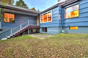A two-story house with a covered porch, a visible staircase, and a well-maintained lawn with scattered leaves. - Downtown Anchorage Home, 1 Block to Coastal Trail! (Anchorage)