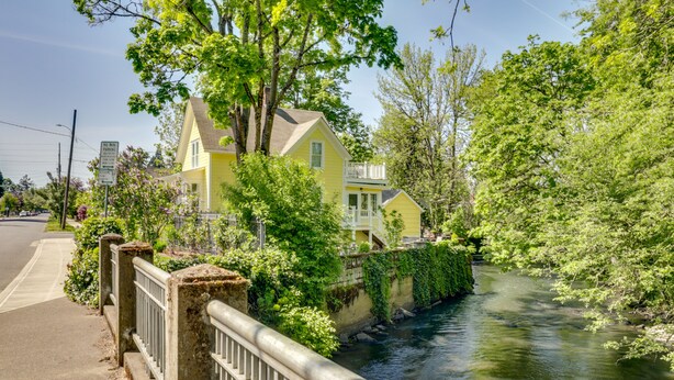 A yellow house with a balcony, a river, and a sidewalk. - Historic Home Near Downtown Salem: Walk to Capitol (Salem)