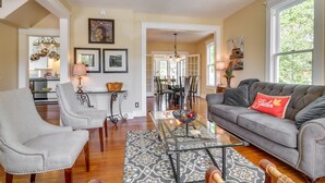 A spacious living room with a gray sofa, a glass coffee table, and a dining area in the background. - Historic Home Near Downtown Salem: Walk to Capitol (Salem)