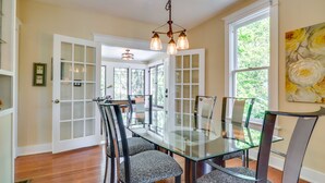 A dining area with a glass-top table and chairs, white-framed glass doors, and a chandelier. - Historic Home Near Downtown Salem: Walk to Capitol (Salem)