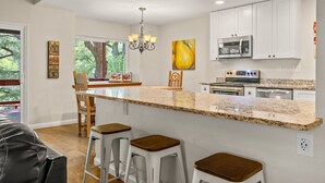 Una cocina moderna con una isla central, armarios blancos y electrodomésticos de acero inoxidable.