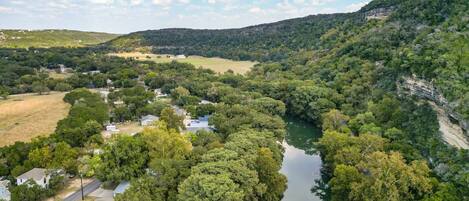 Un río serpentea por una zona boscosa densa con un pequeño asentamiento a orillas del río.